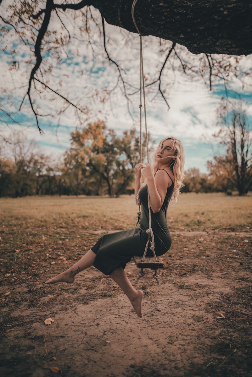 woman in black tank top and black shorts sitting on swing during daytime