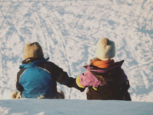 two people sitting on snow during daytime