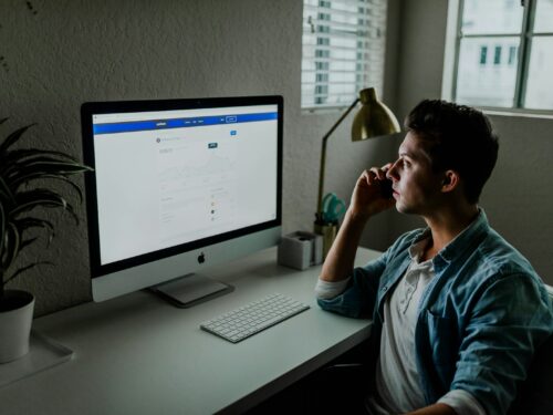 man in blue denim jacket facing turned on monitor