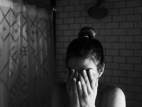 grayscale photo of woman covering her face with her hands