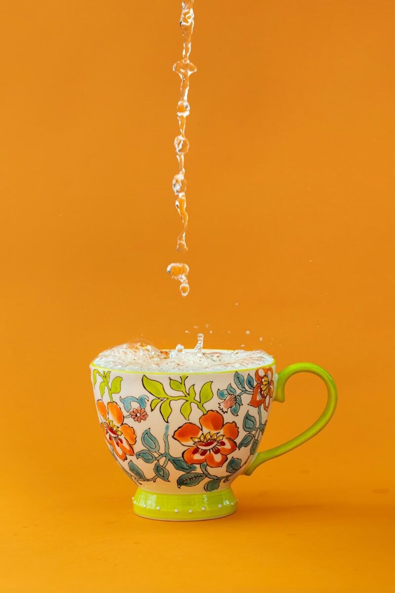 Water splashes into a colorful floral teacup