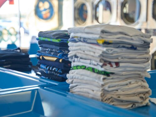 a stack of folded shirts sitting on top of a blue table