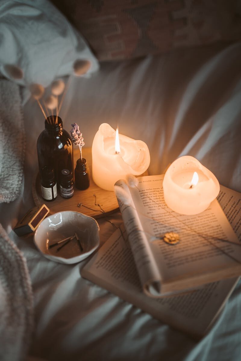 Warm, inviting bedroom setting with candles, books, and soft lighting creating a cozy atmosphere.