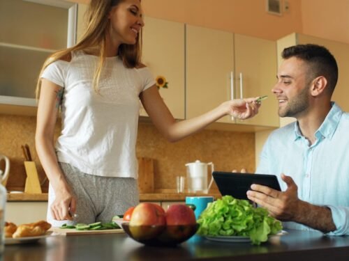 Couple smiling and talking in a kitchen.