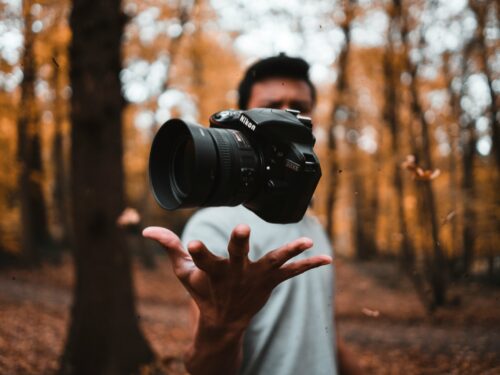 black DSLR camera floating over man's hand at the woods