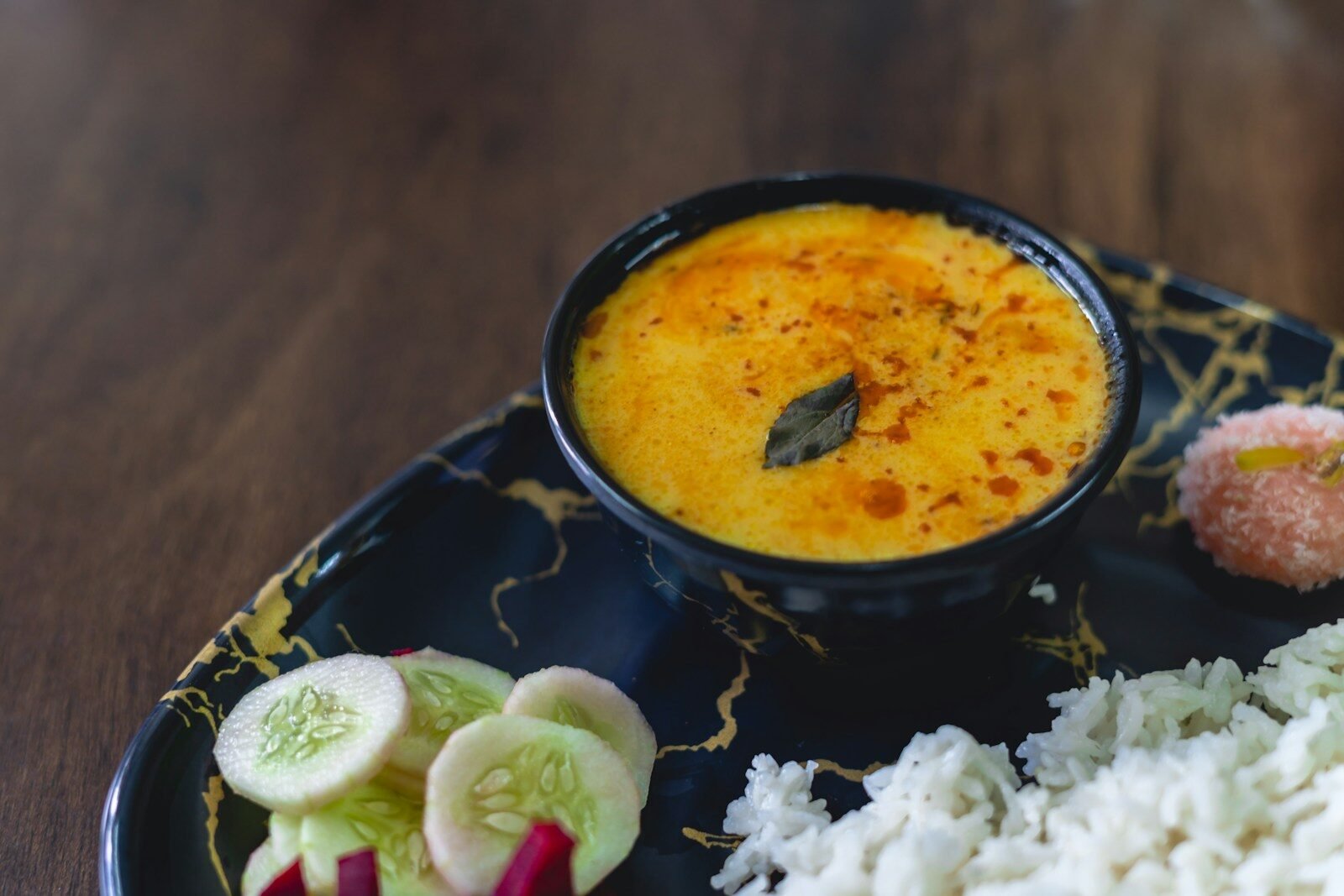 A plate of food with rice, cucumbers, and sauce