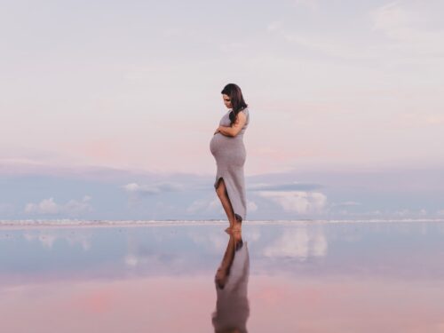 pregnant woman standing on calm body of water