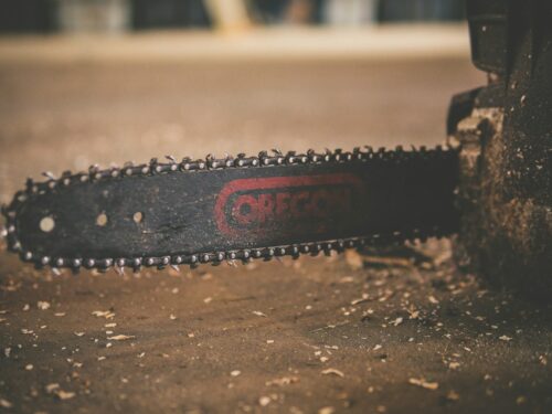 black and red Oregon chainsaw on brown wood plank