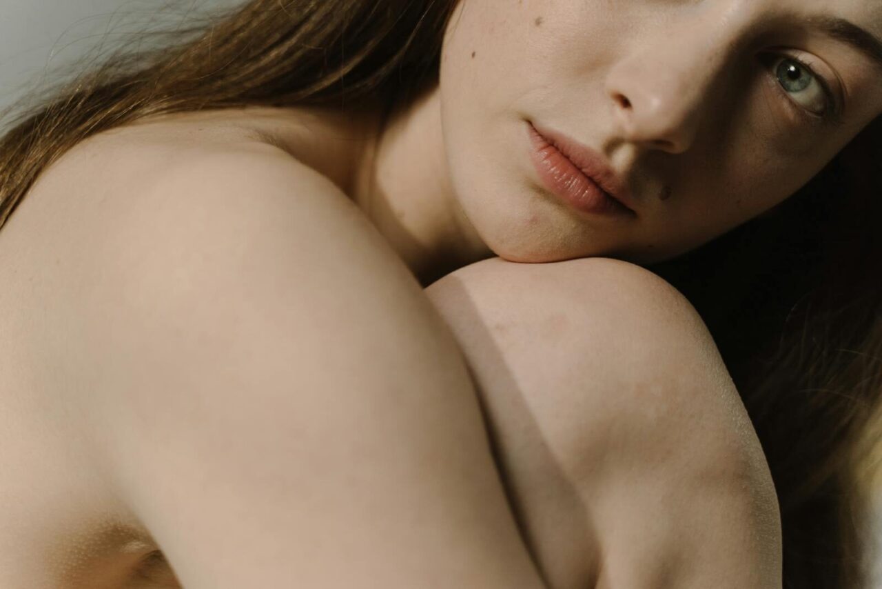 Sensual close-up portrait of a woman with bare skin and intimate expression, highlighting natural beauty.