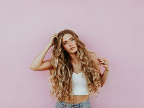 woman standing next to pink wall while scratching her head