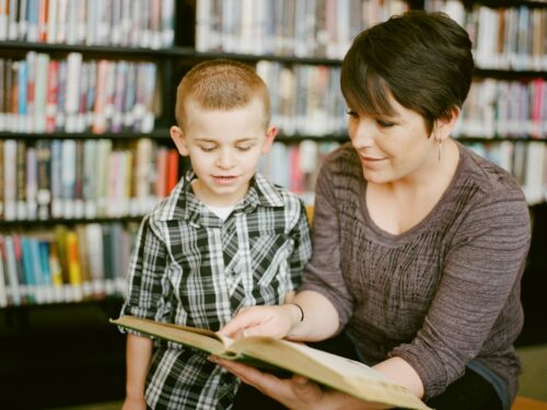 boy in gray sweater beside boy in gray and white plaid dress shirt