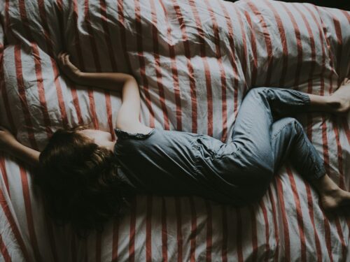 kid sleeping on red and gray bed