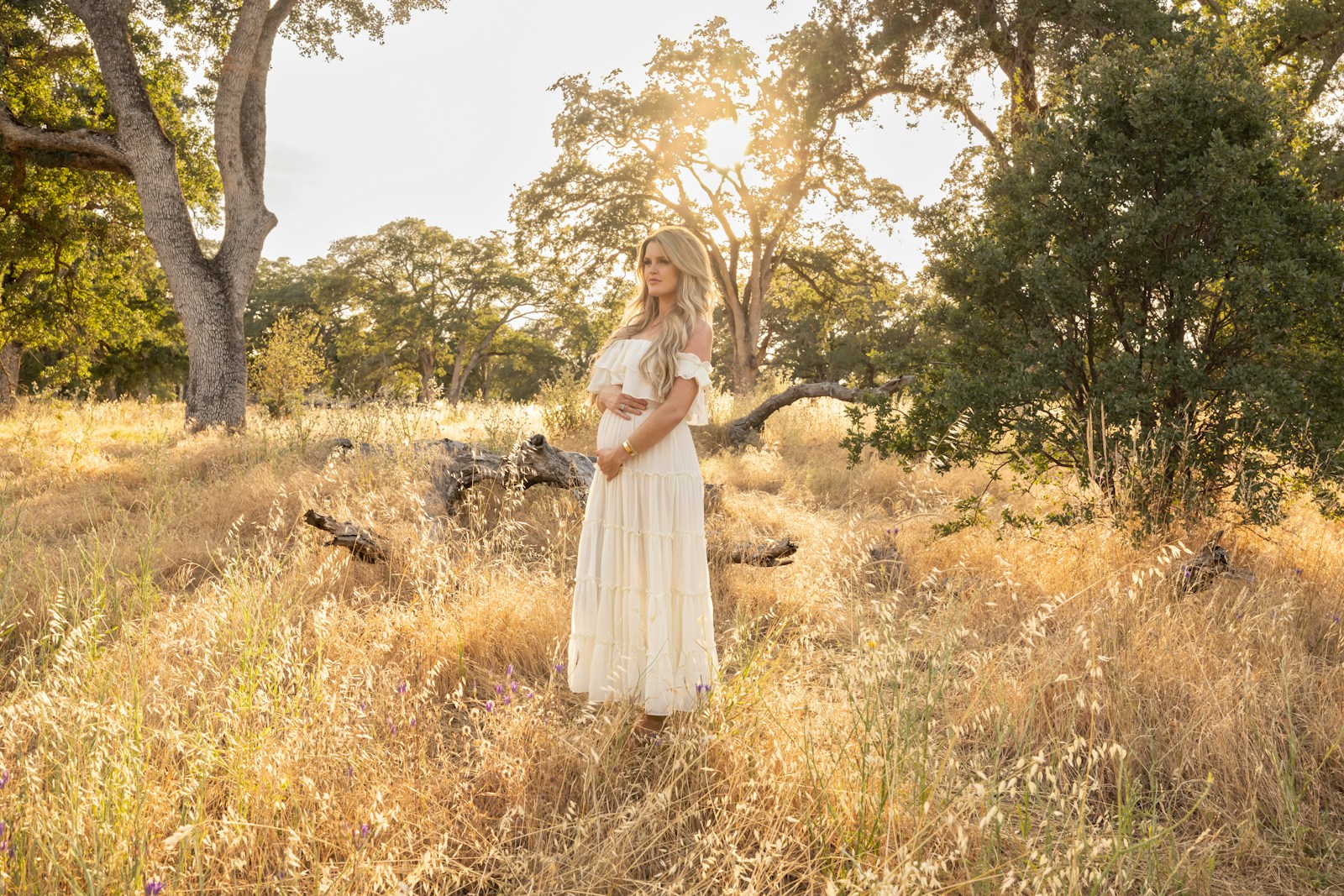 a woman in a white dress standing in a field