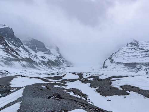 a snow covered mountain range with a cloudy sky