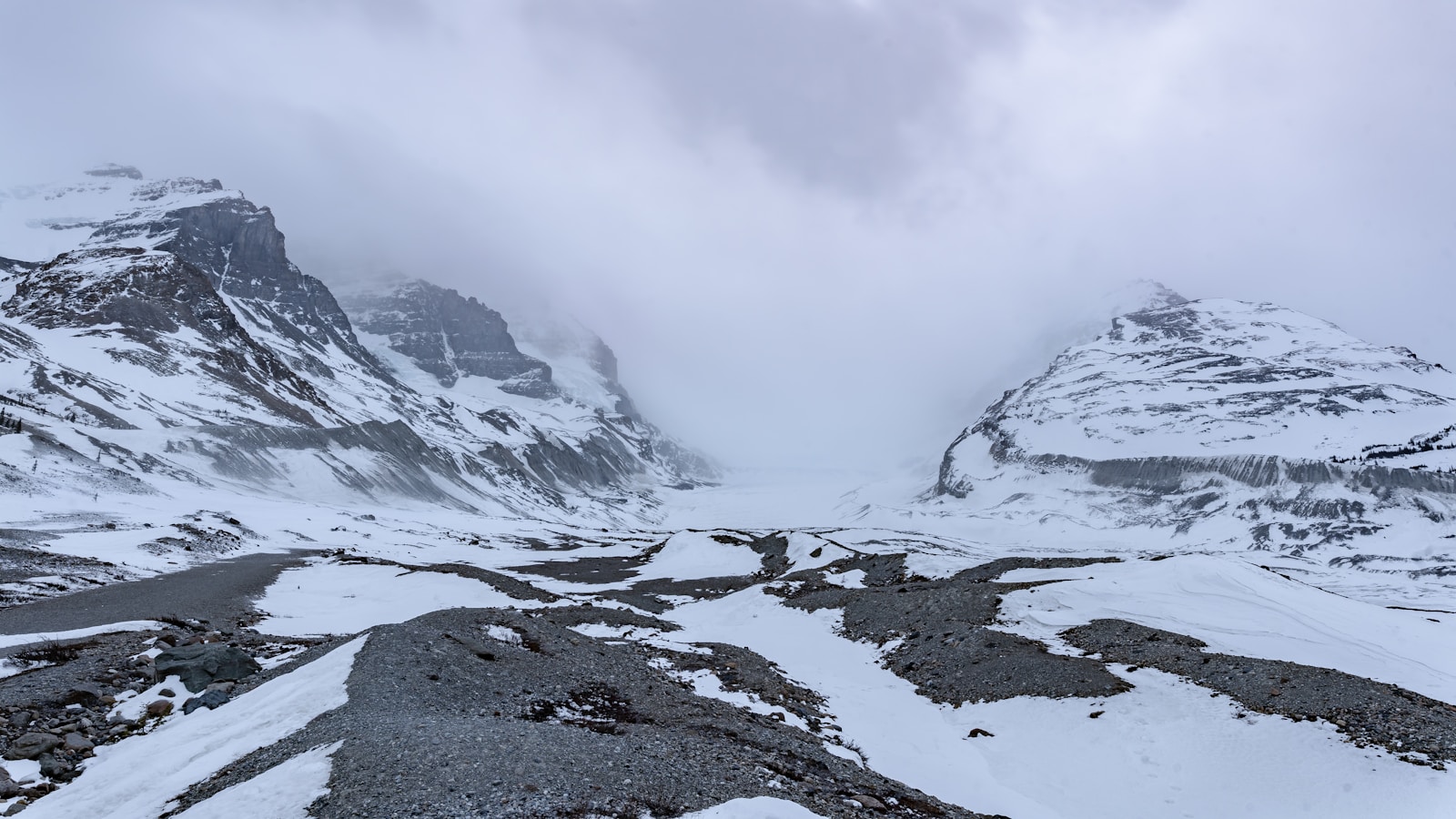 a snow covered mountain range with a cloudy sky