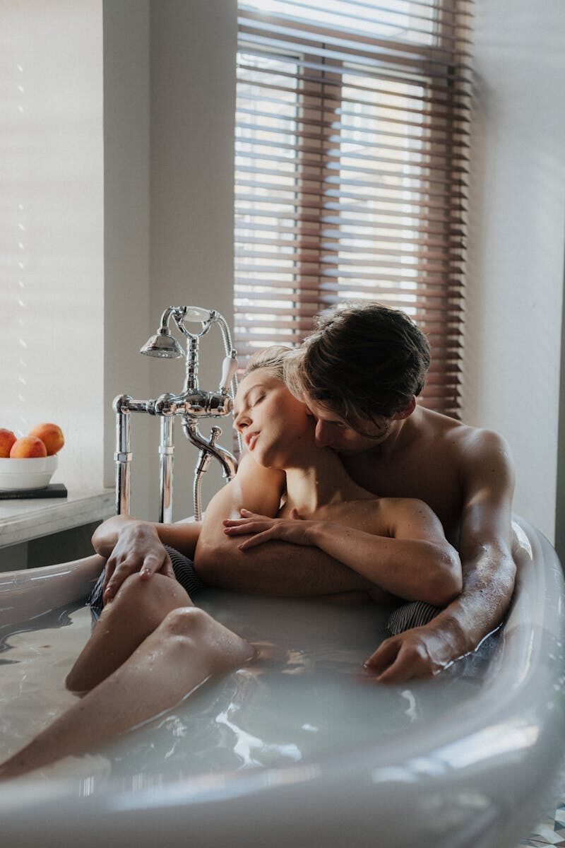 Couple sharing an intimate moment while bathing together in a luxurious bathtub.