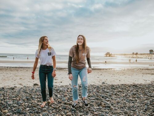 two women walking on pebbles