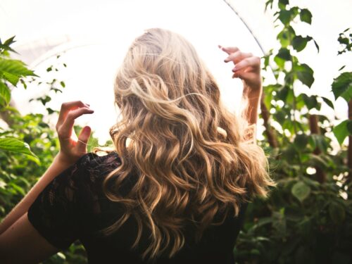 blonde haired woman in black top surrounded by tall plants