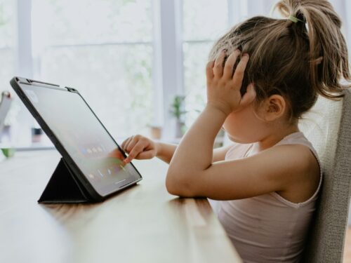 girl in white tank top using black tablet computer