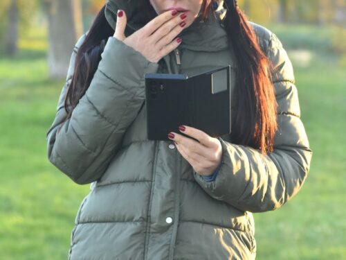 a woman standing in a park holding a tablet