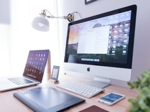 silver iMac near iPhone on brown wooden table