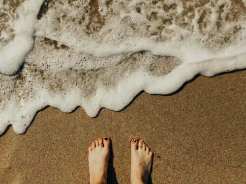 person's feet on seashore