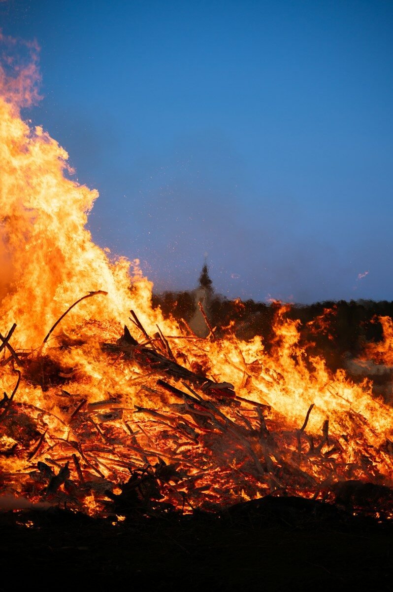 A huge fire burns against a dusk sky