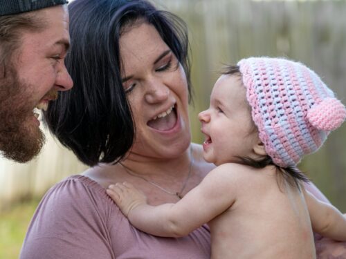 woman in pink knit cap carrying baby in pink knit cap