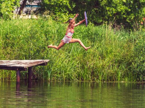 woman in bikini lying on wooden dock during daytime