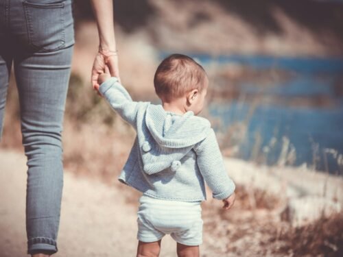 toddler's walking on the seashore with adult