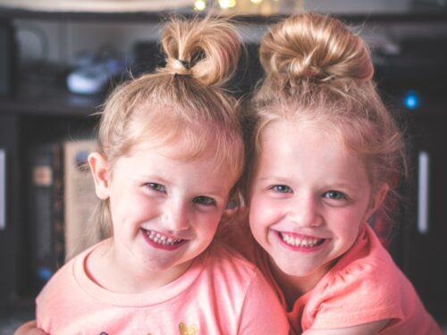 girl in pink crew neck t-shirt smiling beside girl in pink t-shirt