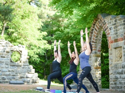 3 women doing yoga on gray concrete floor during daytime