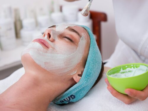 woman lying on blue towel with white cream on face