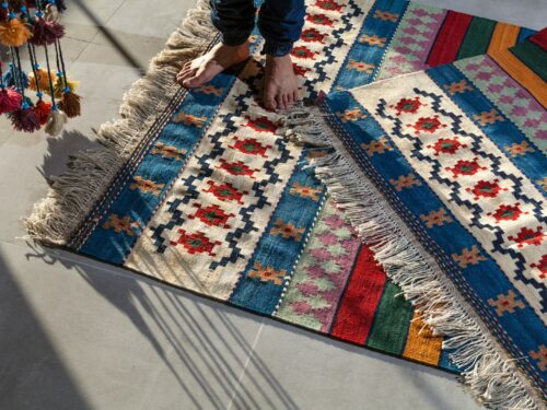 person in blue denim jeans standing on white blue and red area rug