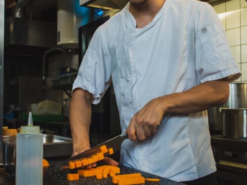 man wearing white shirt slicing inside kitchen