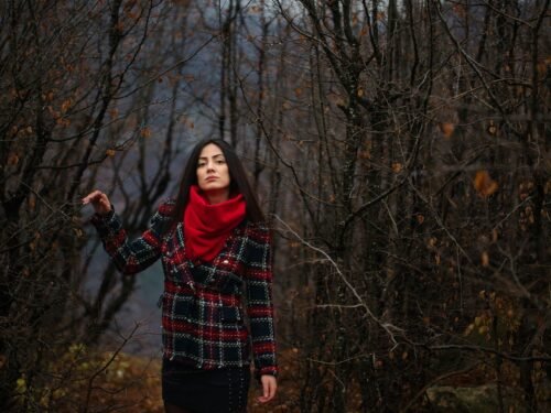 a woman in a red scarf is standing in the woods