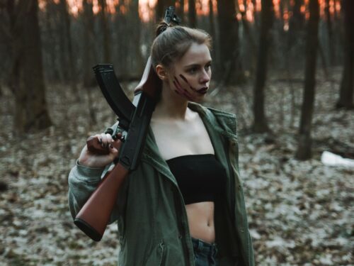 woman in black leather jacket holding black rifle