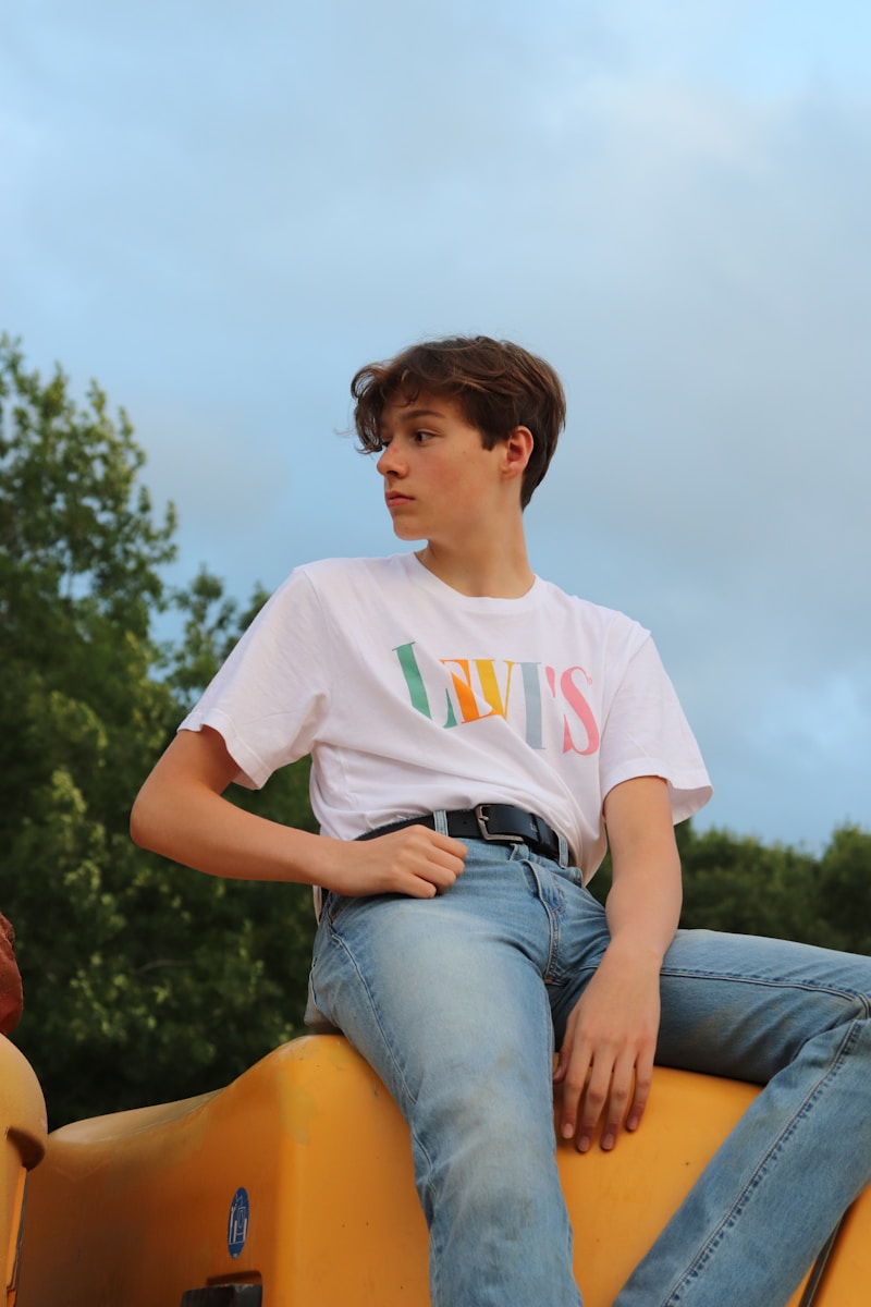 woman in white crew neck t-shirt and blue denim shorts sitting on brown wooden bench