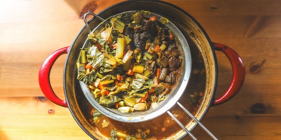 strainer with vegetables and broth