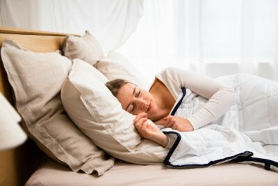 a woman sleeping in a bed with a white comforter