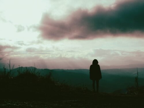a person standing on top of a hill under a cloudy sky