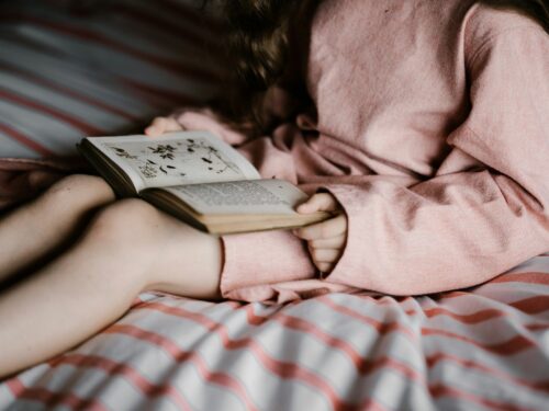 woman reading book on white and red textile