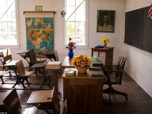 vacant white painted classroom with chairs, tables , and map on the wall