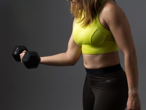 woman wearing pink sports bra holding dumbbells