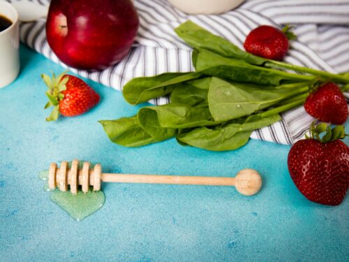 brown honey dipper beside strawberries and apple