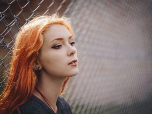 woman leaning on gray fence