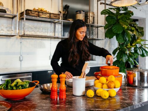 woman standing in front of fruits holding pot's lid