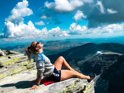 woman sitting on peak of mountain