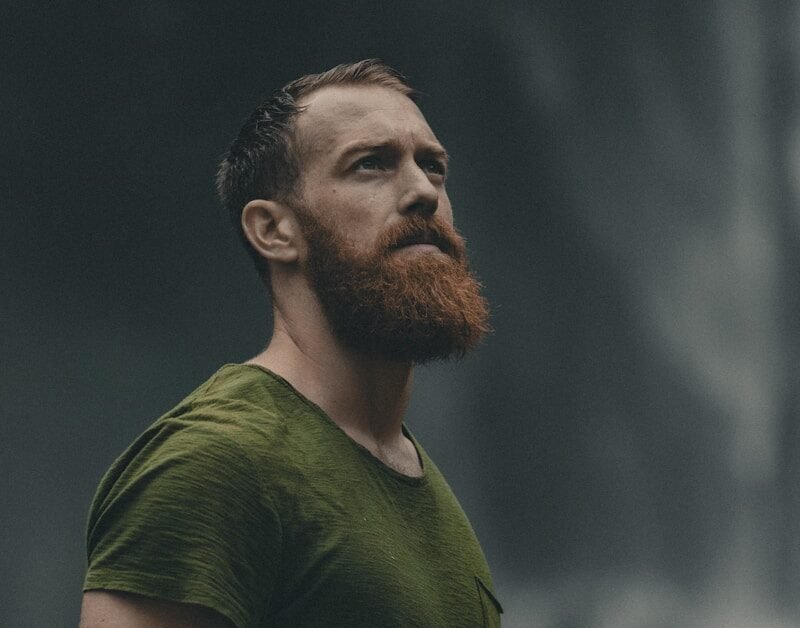 man wearing green crew-neck t-shirt looking upwards