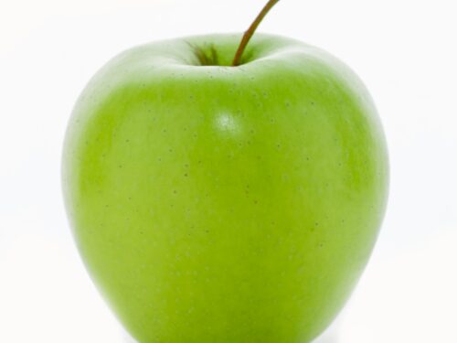 a green apple sitting on top of a white table